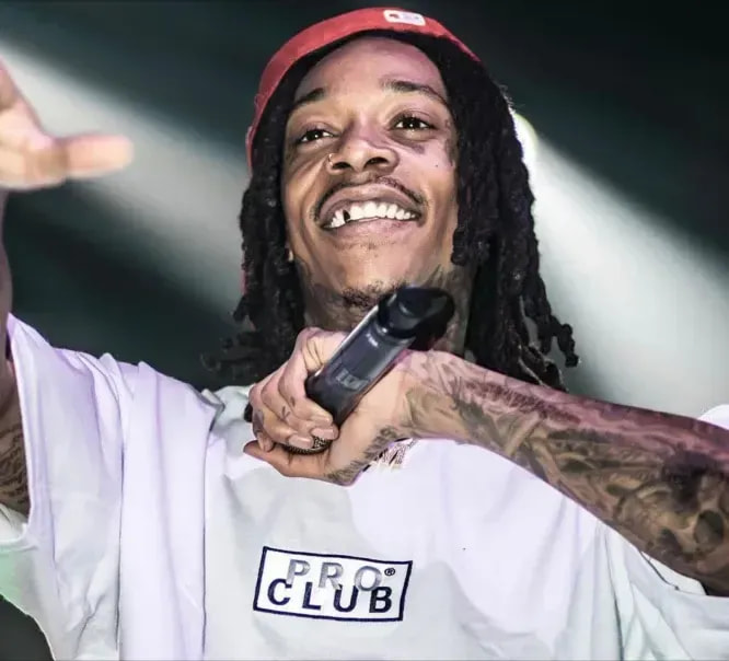 Wiz Khalifa performing in a white Pro Club t-shirt and red cap