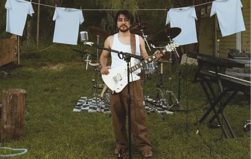 Musician performing in a backyard hung with white tees