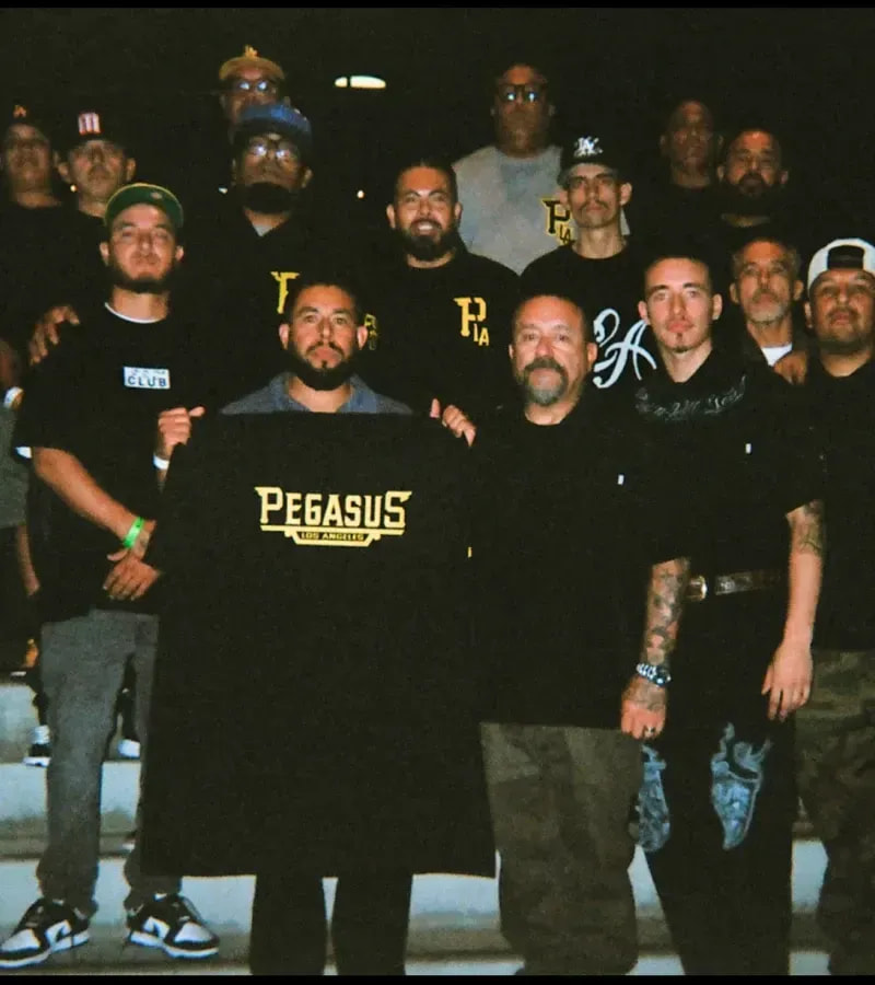 Group at night holding a Pro Club × Pegasus tee
