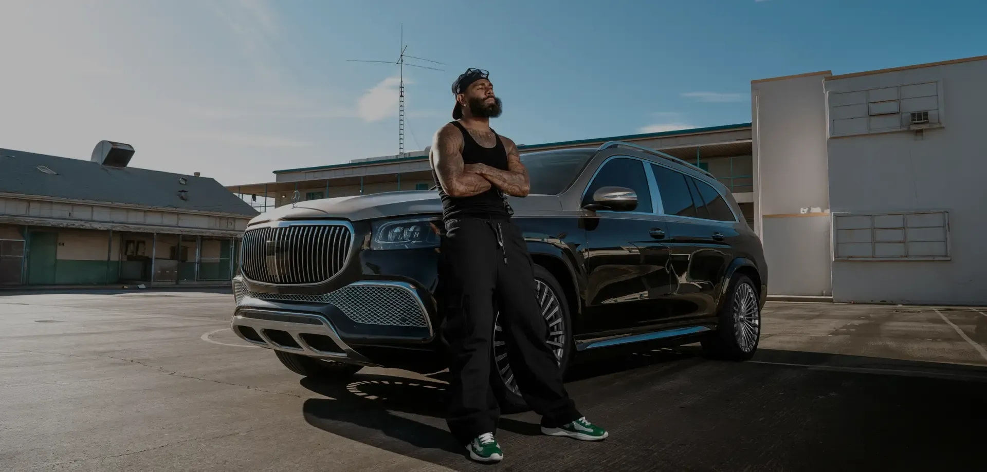 Man in a black Pro Club Heavyweight Performance Tank and pants beside a black Mercedes-Maybach SUV