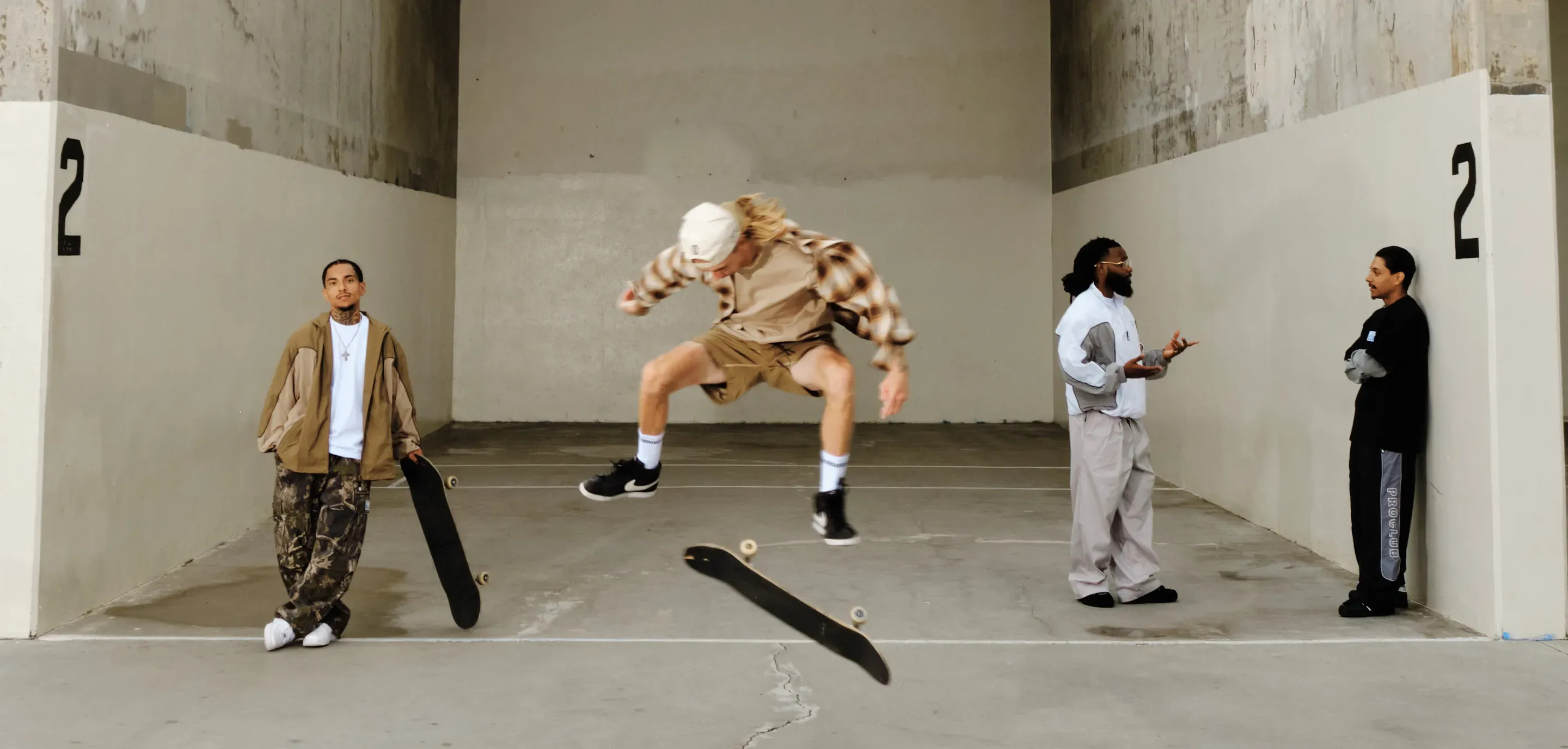 Pro Club skaters in casual streetwear, with one skateboarder mid-air and others standing around in a concrete skate space.