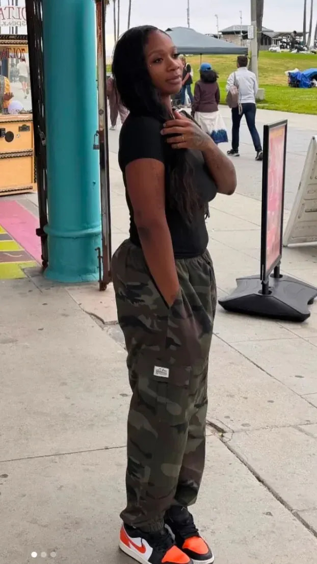 Woman in a black Pro Club tee and camo cargos in black and white