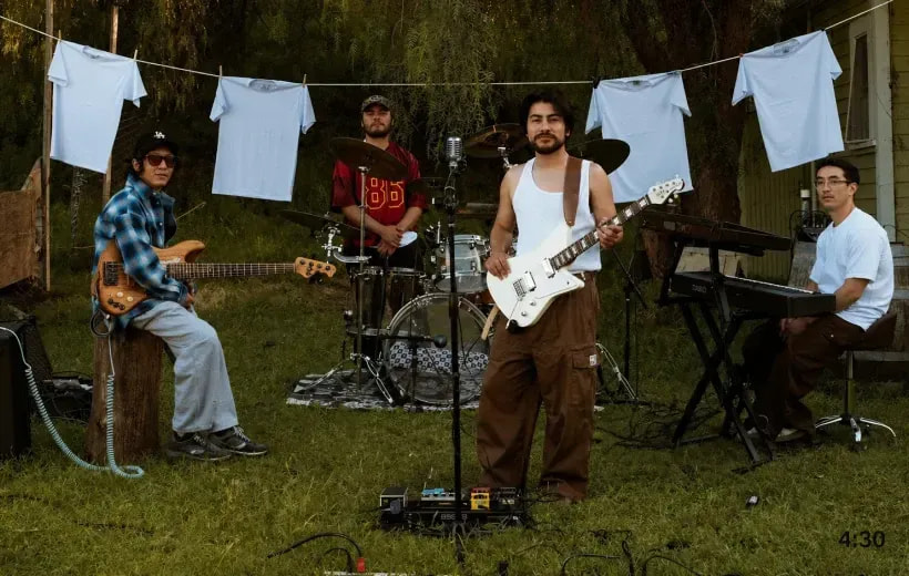 Los Retros band performing in a backyard, singer in a white Pro Club tank