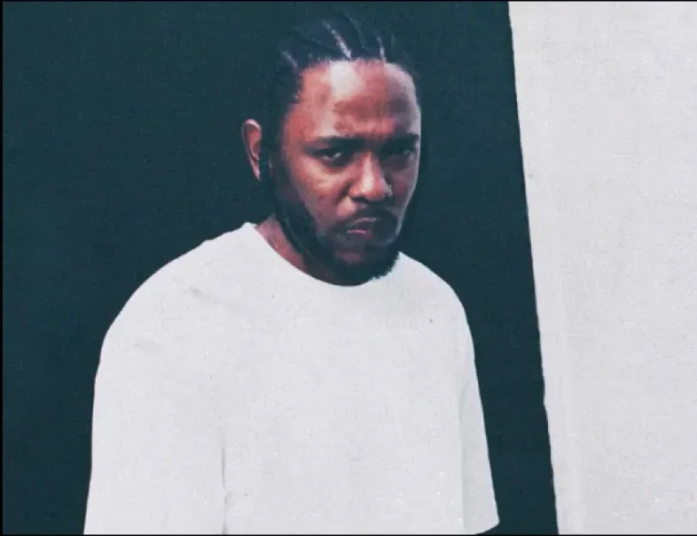 Kendrick Lamar in a white t-shirt against a two-tone wall